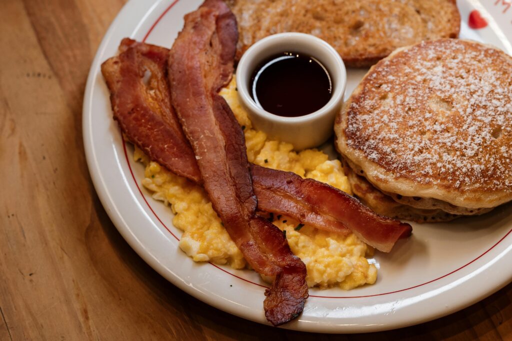 petit déjeuner typique américain avec pancakes, bacon, œufs brouillés, sirop d'érable